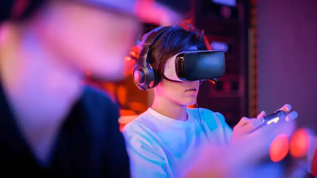 Osoba w goglach VR i słuchawkach trzyma w ręku kontroler do gier, zanurzona w oświetlonym neonami pomieszczeniu. Scena ta oddaje futurystyczny charakter rozgrywki.