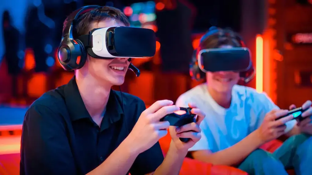 Dwoje ludzi w goglach VR i słuchawkach uśmiecha się i gra w gry wideo za pomocą kontrolerów. Scena rozgrywa się w oświetlonym neonami pomieszczeniu, co oddaje atmosferę podekscytowania.
